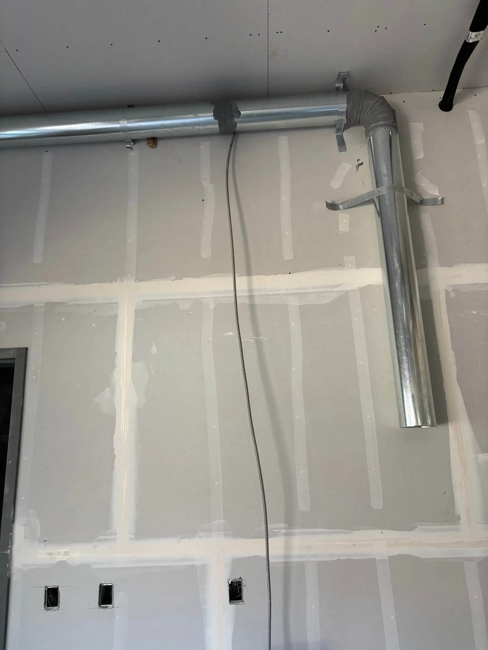 Metal ductwork and piping in drywall ceiling for HVAC system.