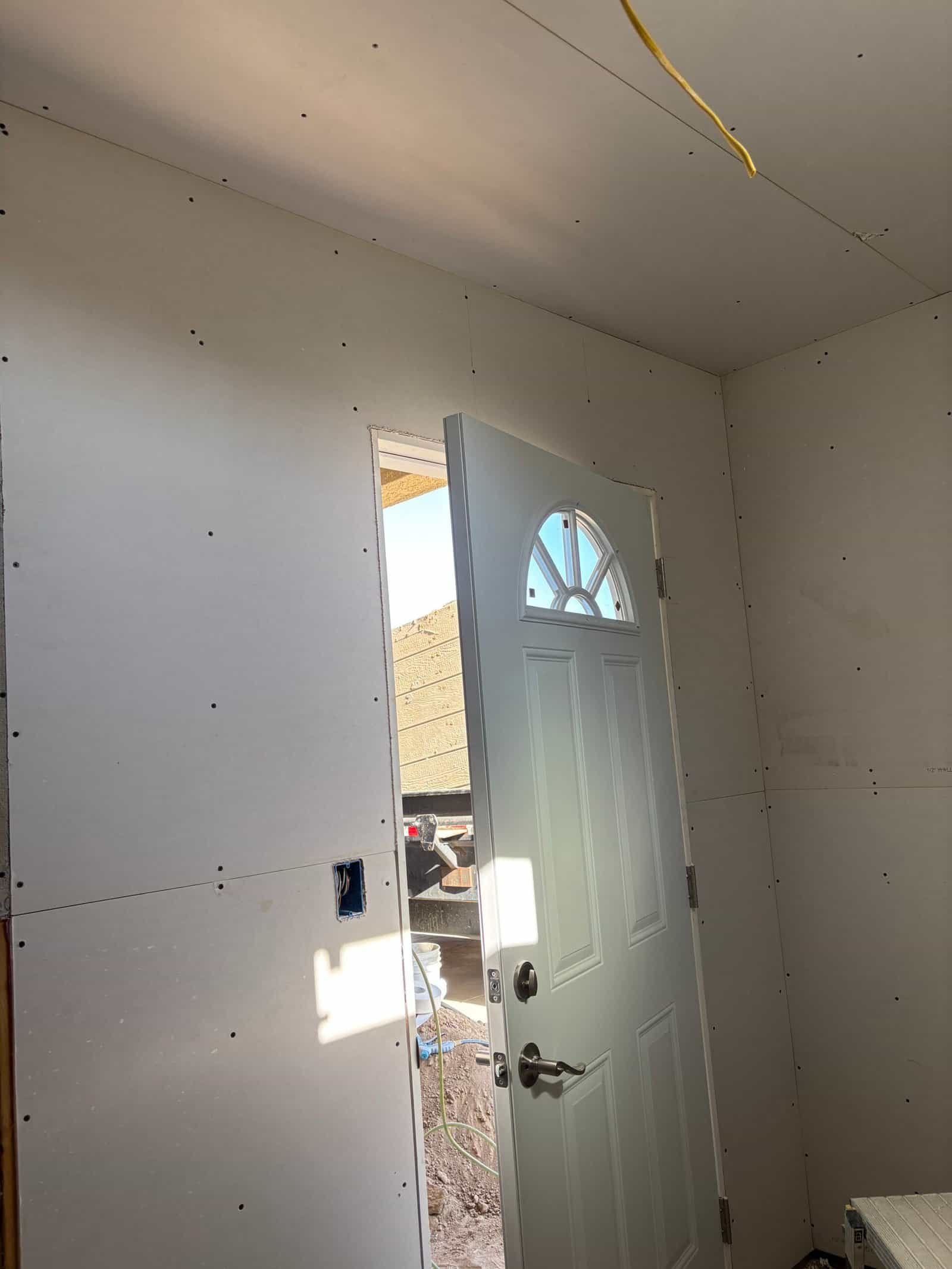 Interior drywall installation with door frame in progress at Priority Drywall.