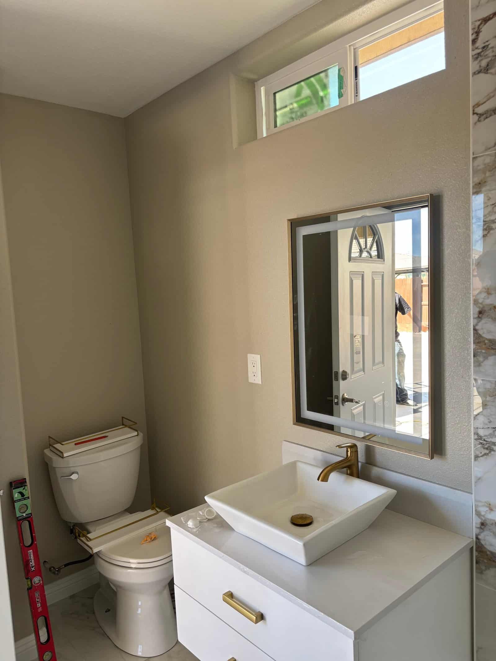 Contemporary bathroom with vanity, mirror, and toilet in new home.