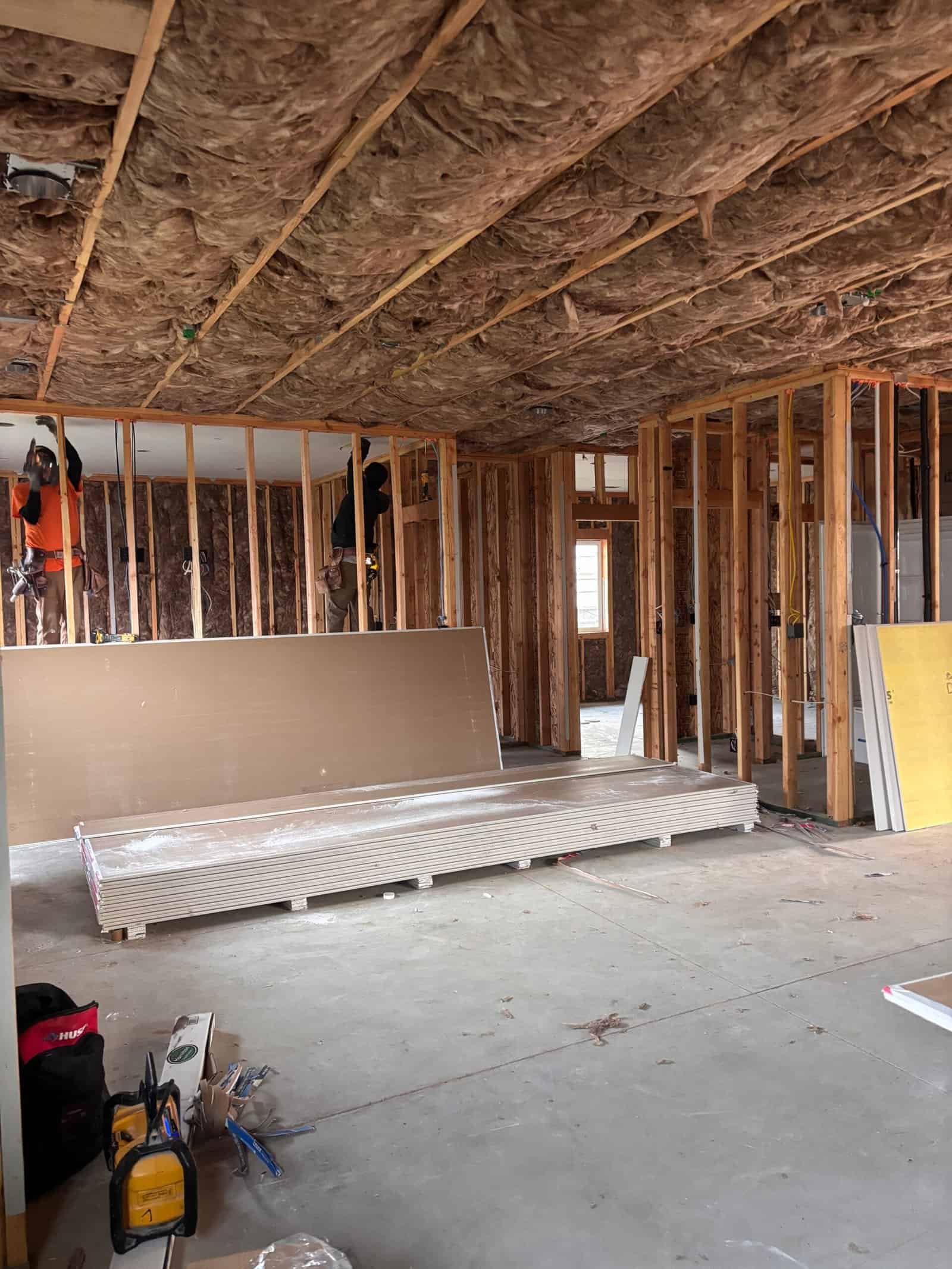 Construction site with framing, insulation, and drywall materials in progress.