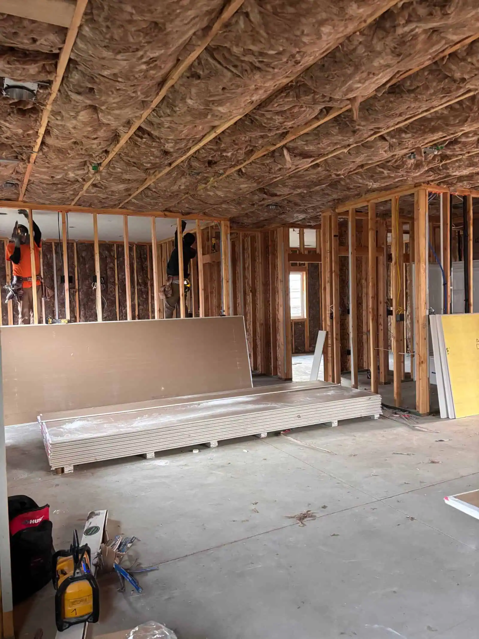 Construction site with framing, insulation, and drywall materials in progress.